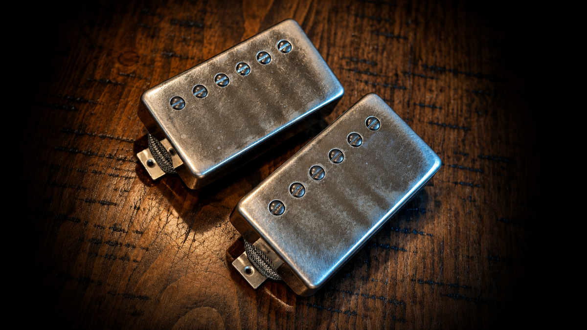 Two aged nickel Brickhouse Toneworks guitar humbucker pickups resting on a dark, textured wooden surface.